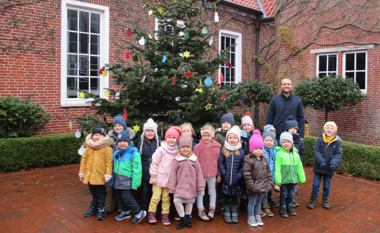 Kindergartenkinder schmücken Weihnachtsbaum vor der Kirche